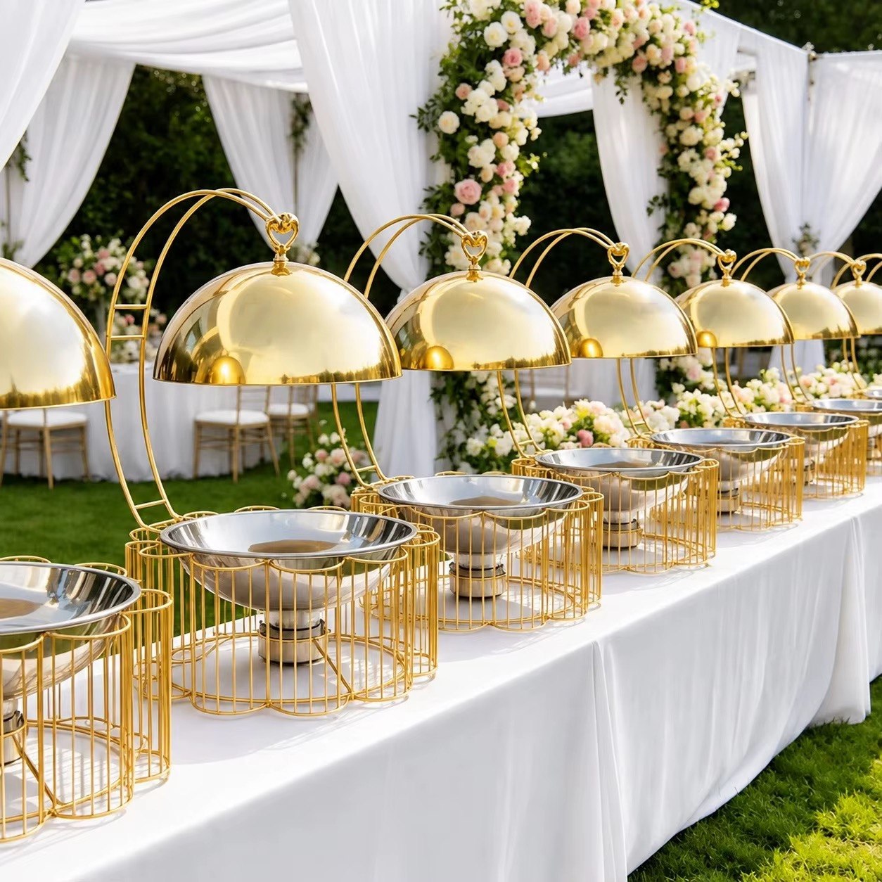 Gold domed buffet serving dishes arranged for an outdoor event